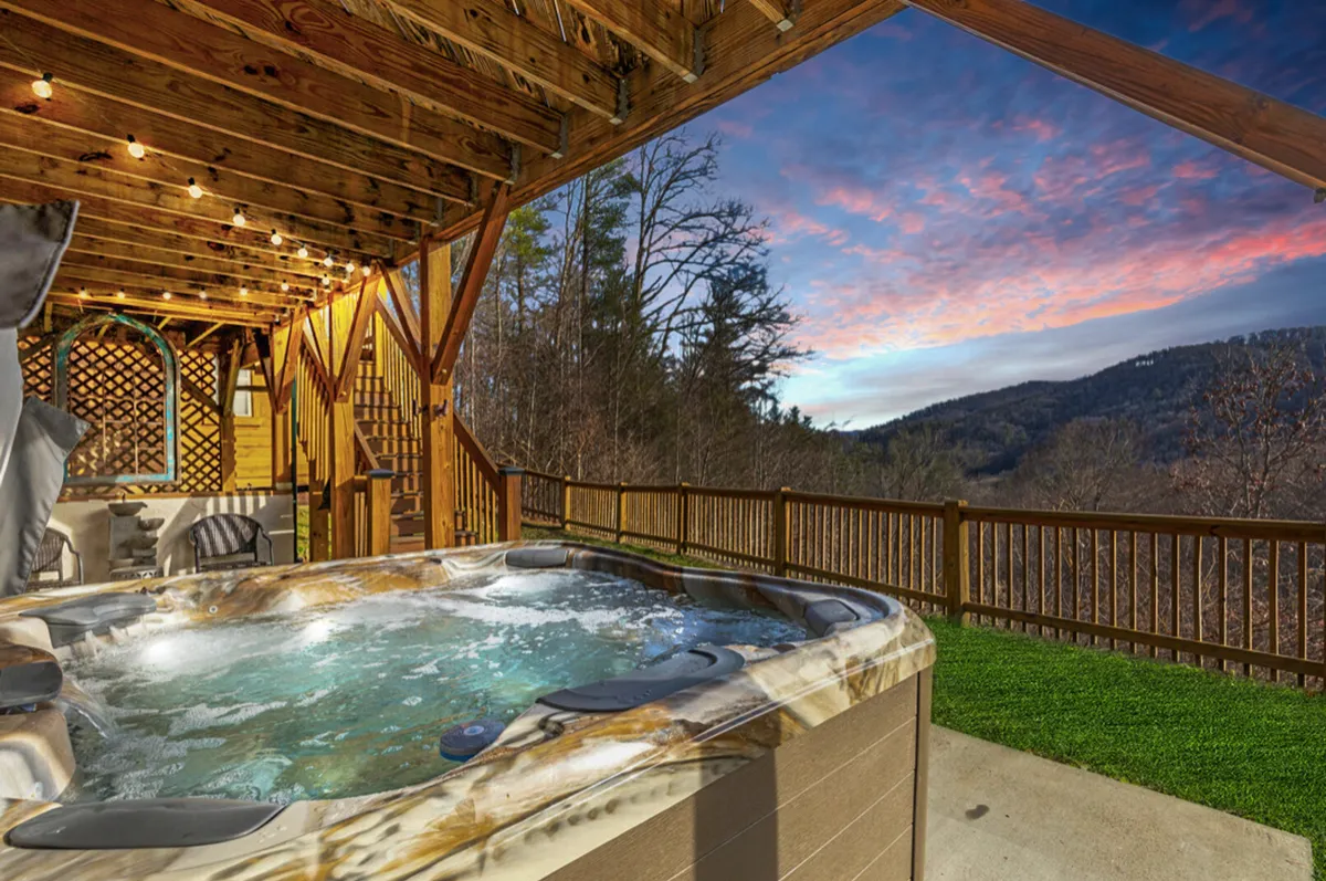 A tranquil hot tub set on a wooden deck, perfectly positioned to overlook sweeping mountain vistas. The setting is ideal for relaxing soaks at sunset or under the stars, with the expansive landscape providing a picturesque backdrop.